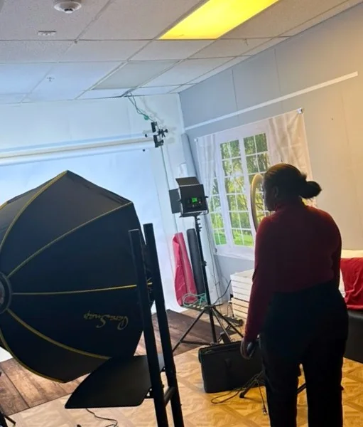 A room inside the center with a softbox light, white backdrop, and a window with green trees.